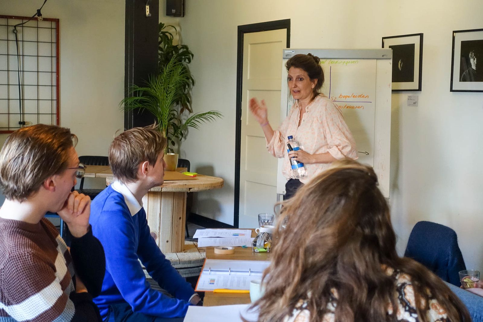 Trainer Céline bespreekt met een groep jonge leidinggevenden hoe je als leider sturend en ondersteunend gedrag combineert. 